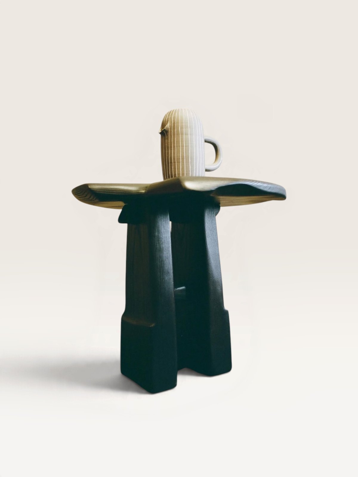 Dark sculptural stool with ceramic vessel